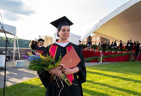 image of adult graduate student with diploma and flowers in hand