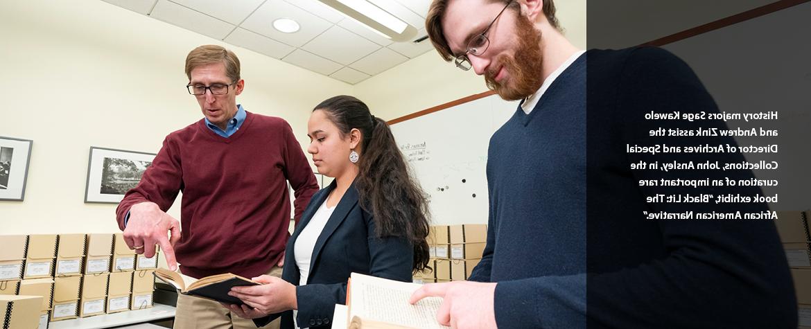 History majors Sage Kawelo and Andrew Zink assist the Director of Archives and Special Collections, John Ansley, in the curation of an important rare book exhibit, “Black Lit: The African American Narrative.