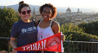 Two girls are posing for a picture with Marist sign